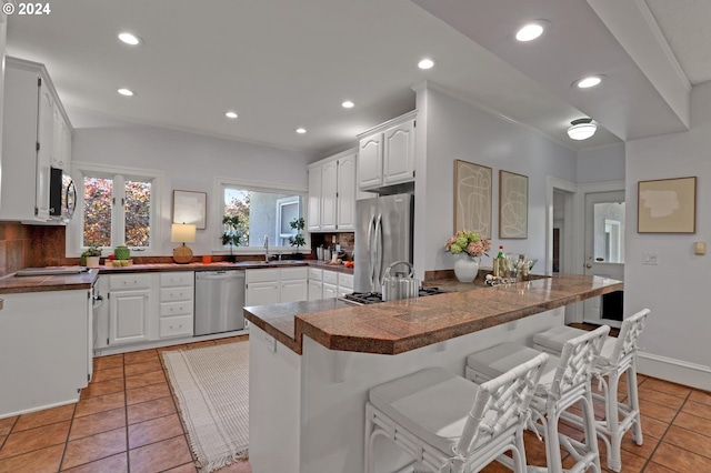 kitchen featuring appliances with stainless steel finishes, kitchen peninsula, a kitchen bar, and backsplash