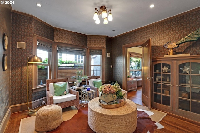 living area with ornamental molding, a notable chandelier, and wood-type flooring