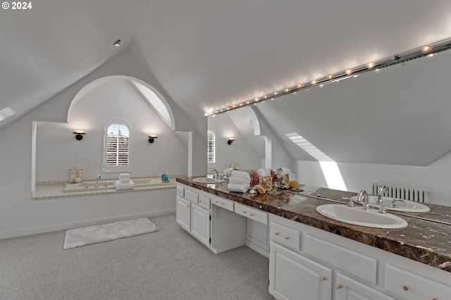 bathroom with vanity, vaulted ceiling, and a washtub