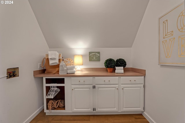 bar with vaulted ceiling, light wood-type flooring, and white cabinets