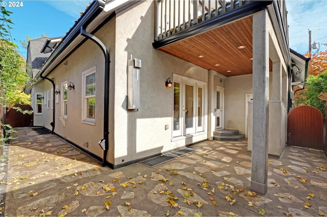 view of property exterior featuring a patio, french doors, and a balcony