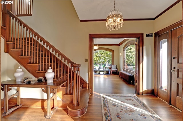 foyer with ornamental molding, an inviting chandelier, and hardwood / wood-style floors