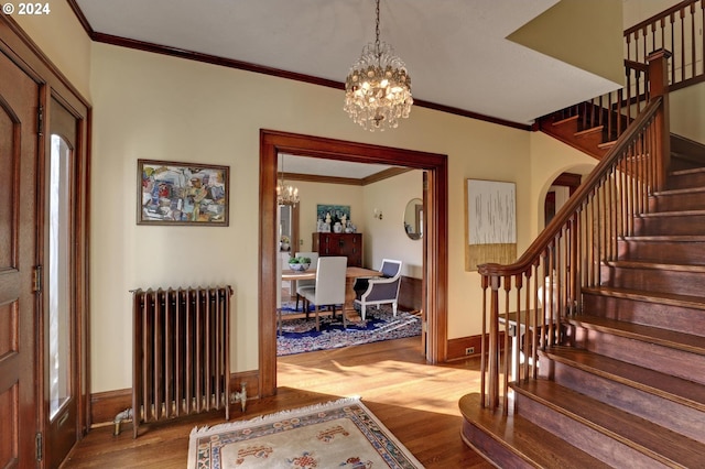 entryway featuring radiator, light hardwood / wood-style floors, a notable chandelier, and crown molding