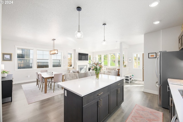 kitchen with hanging light fixtures, a center island, a textured ceiling, and dark hardwood / wood-style floors