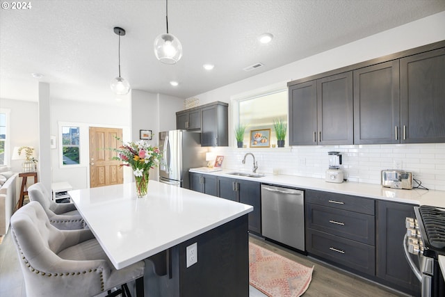 kitchen featuring a kitchen bar, sink, a kitchen island, pendant lighting, and stainless steel appliances