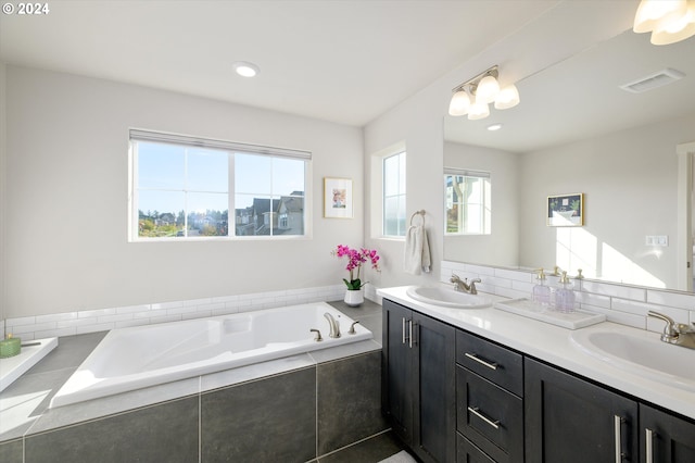 bathroom with an inviting chandelier, vanity, decorative backsplash, and tiled tub