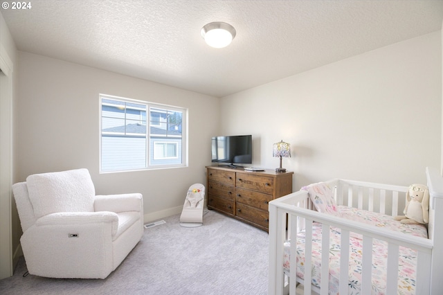 carpeted bedroom featuring a textured ceiling and a crib