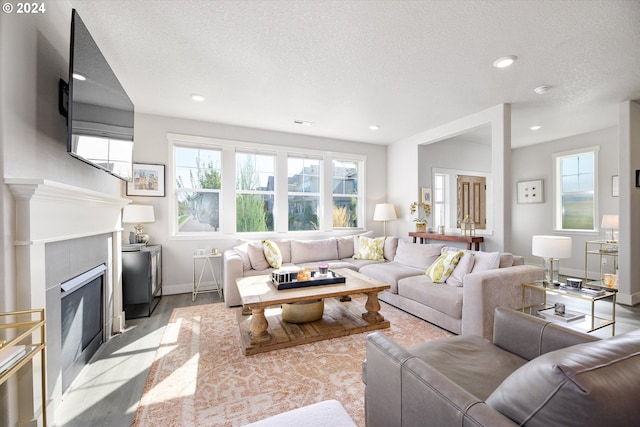 living room featuring a premium fireplace, a textured ceiling, and light hardwood / wood-style flooring