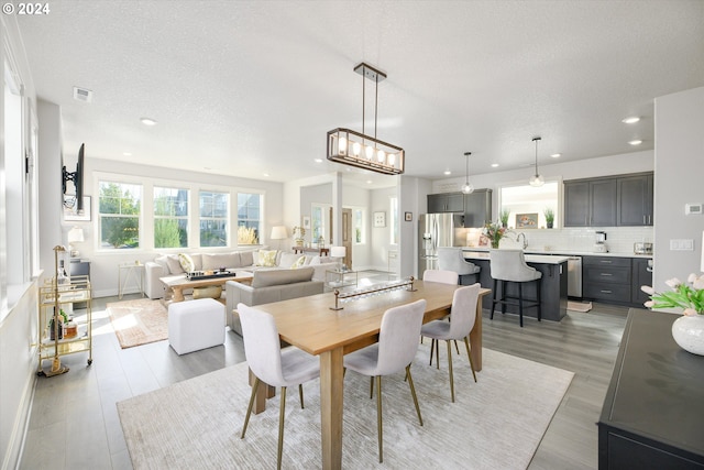 dining space featuring sink, light hardwood / wood-style floors, and a textured ceiling