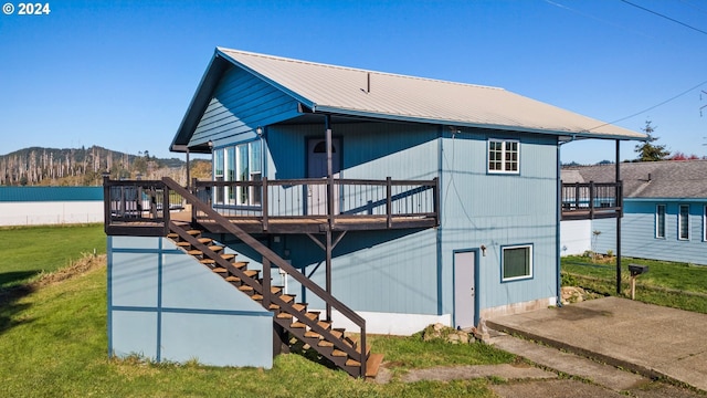 back of property featuring a deck with mountain view and a yard