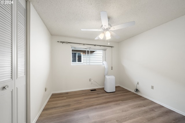 unfurnished bedroom with hardwood / wood-style floors, ceiling fan, a textured ceiling, and a closet