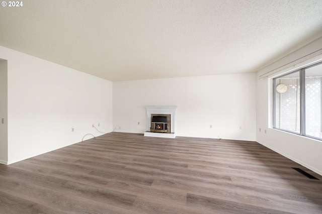 unfurnished living room with a textured ceiling and dark hardwood / wood-style floors