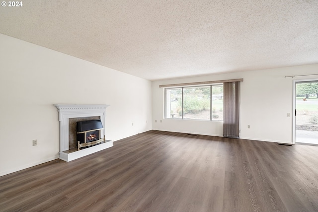 unfurnished living room with dark wood-type flooring, a textured ceiling, and plenty of natural light