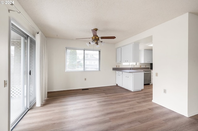 kitchen featuring white cabinetry, light wood-type flooring, dishwasher, and a textured ceiling