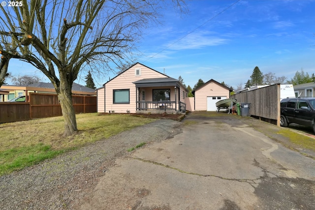 view of front facade with aphalt driveway, a porch, fence, an outdoor structure, and a front lawn