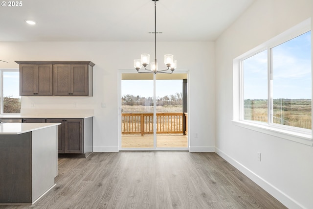 unfurnished dining area with light hardwood / wood-style flooring, a wealth of natural light, and an inviting chandelier