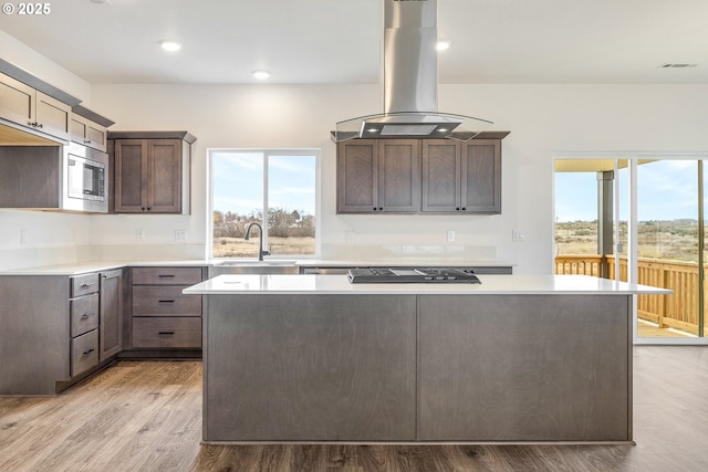 kitchen featuring a kitchen island, sink, island range hood, and stainless steel microwave