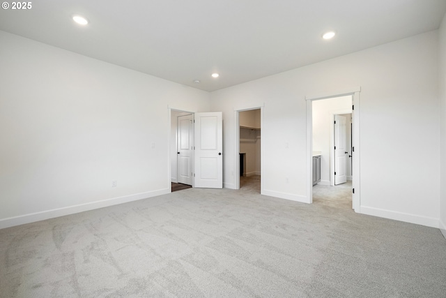 unfurnished bedroom with a spacious closet and light carpet