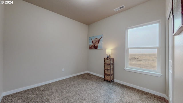 unfurnished room with carpet, visible vents, and baseboards