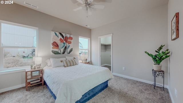 bedroom with carpet, a walk in closet, visible vents, and baseboards