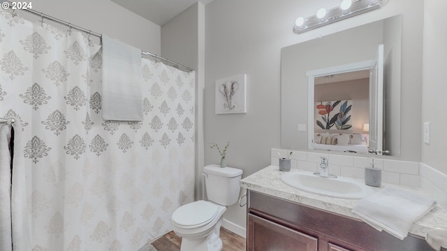 bathroom with toilet, ensuite bath, wood finished floors, curtained shower, and vanity