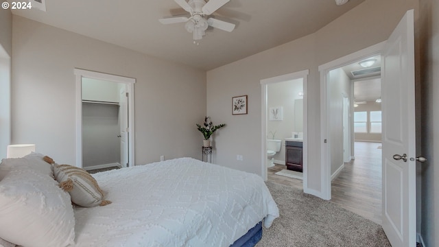 bedroom with a walk in closet, a closet, visible vents, connected bathroom, and baseboards