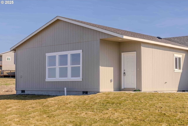 rear view of property featuring crawl space, a shingled roof, and a yard