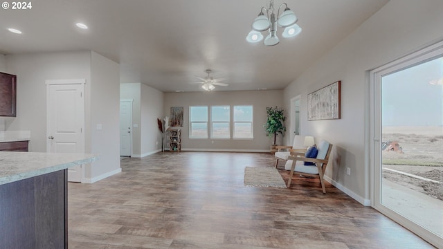 living area with recessed lighting, baseboards, light wood finished floors, and ceiling fan with notable chandelier