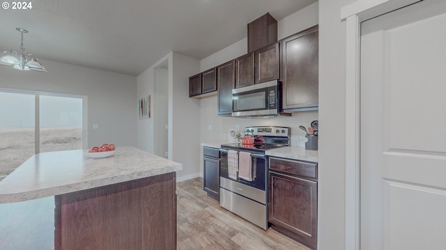 kitchen with dark brown cabinetry, a notable chandelier, stainless steel appliances, light countertops, and light wood-type flooring