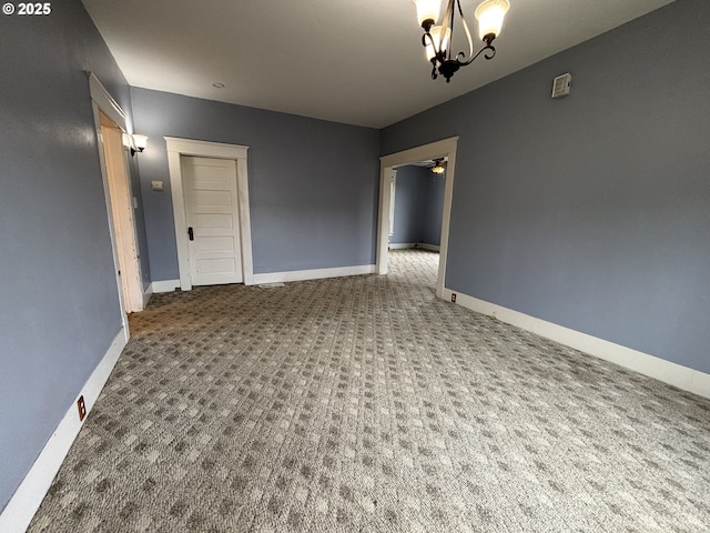 carpeted empty room featuring ceiling fan with notable chandelier