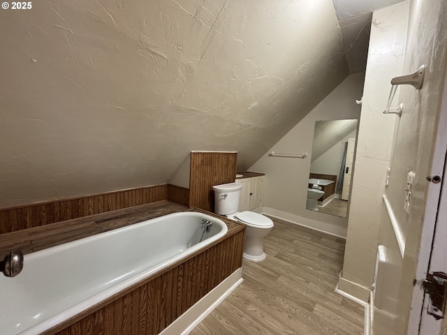 bathroom with a washtub, vanity, wood-type flooring, and lofted ceiling