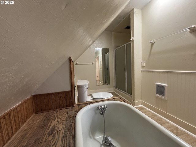 bathroom featuring hardwood / wood-style floors, lofted ceiling, toilet, wooden walls, and a bathtub