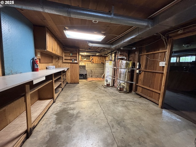 basement featuring a workshop area, wood walls, and gas water heater