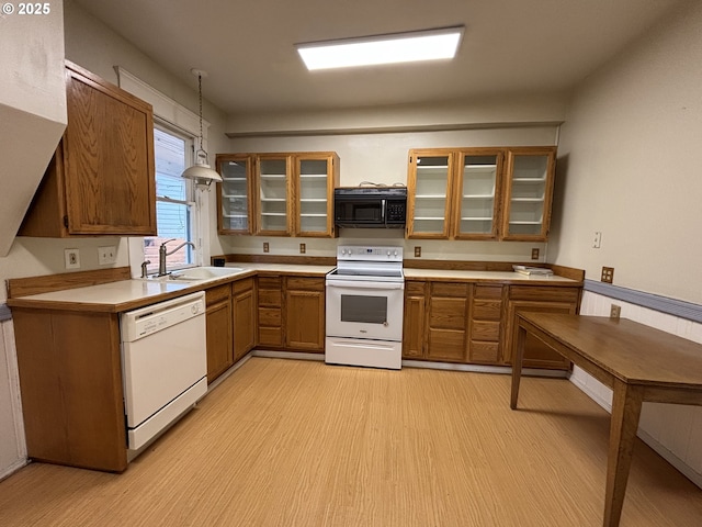 kitchen featuring light wood-type flooring, white appliances, decorative light fixtures, and sink