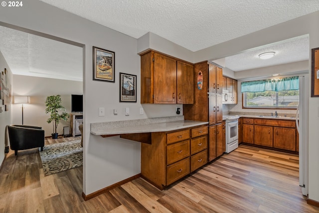 kitchen with kitchen peninsula, electric range, a textured ceiling, light hardwood / wood-style flooring, and sink