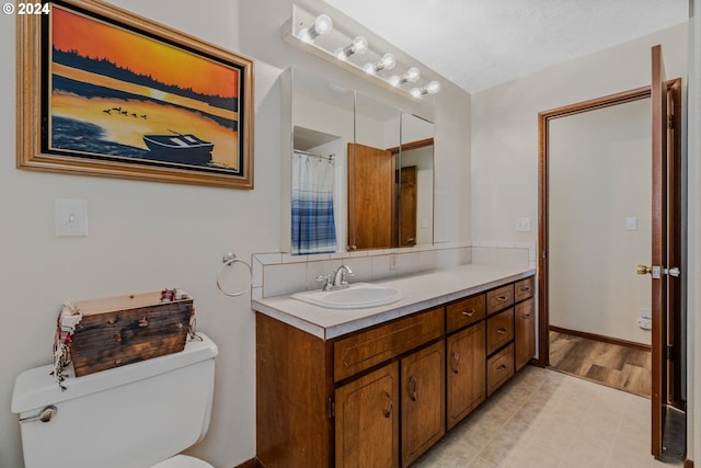 bathroom with toilet, a textured ceiling, vanity, and wood-type flooring