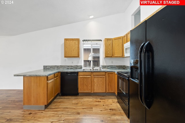 kitchen featuring kitchen peninsula, lofted ceiling, light hardwood / wood-style flooring, black appliances, and sink