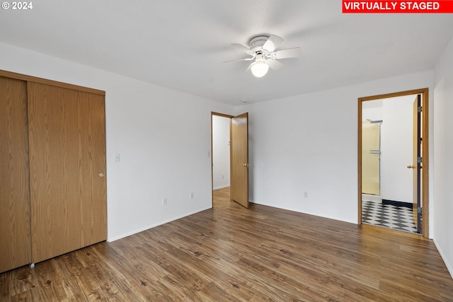 unfurnished bedroom featuring a closet, hardwood / wood-style floors, white refrigerator, and ceiling fan