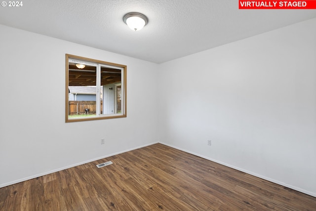 empty room with hardwood / wood-style floors and a textured ceiling