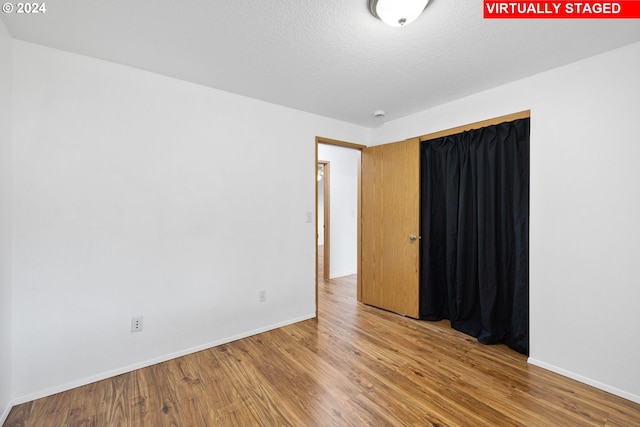 spare room with a textured ceiling and wood-type flooring