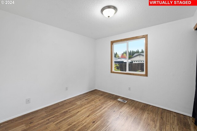 unfurnished room featuring a textured ceiling and hardwood / wood-style flooring