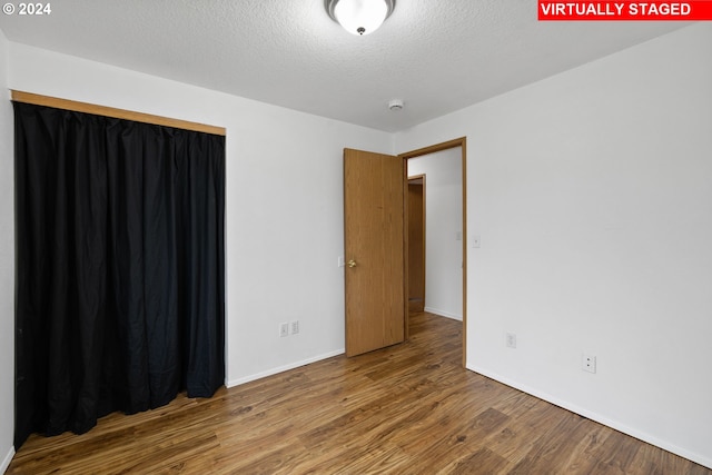 spare room with wood-type flooring and a textured ceiling