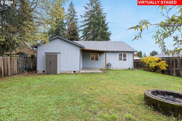 back of property featuring a yard, a storage shed, and an outdoor fire pit