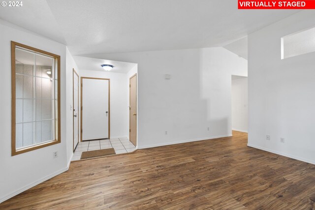 spare room with light hardwood / wood-style floors and lofted ceiling