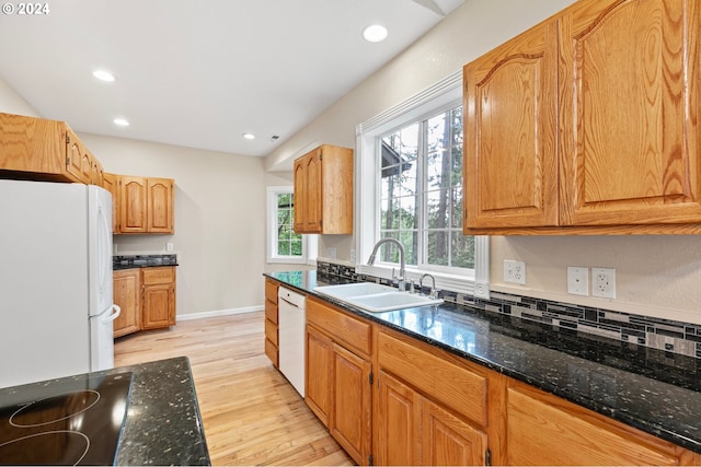 kitchen featuring backsplash, white appliances, sink, light hardwood / wood-style flooring, and dark stone countertops