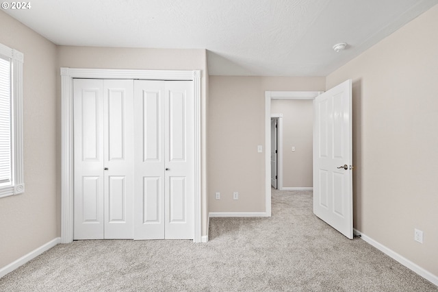 unfurnished bedroom featuring a closet, light colored carpet, and a textured ceiling