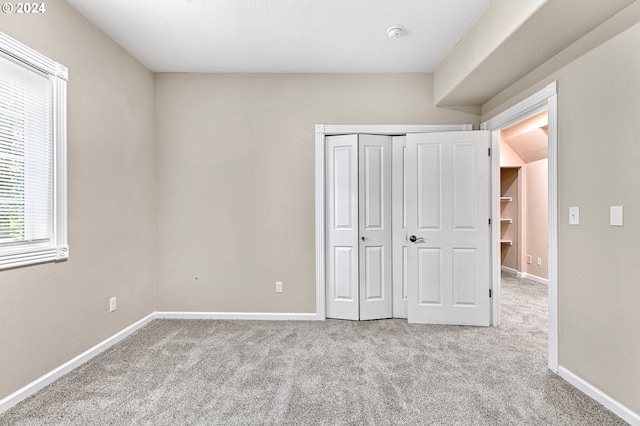 unfurnished bedroom featuring light carpet and a closet