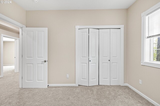 unfurnished bedroom featuring light colored carpet and a closet