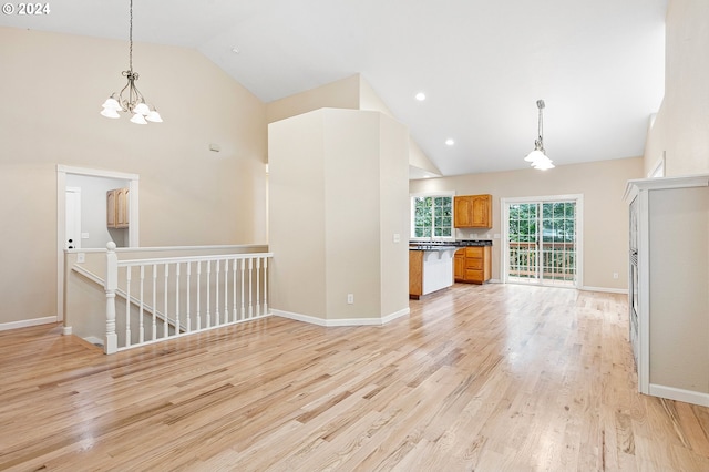 unfurnished living room with a chandelier, high vaulted ceiling, and light hardwood / wood-style floors