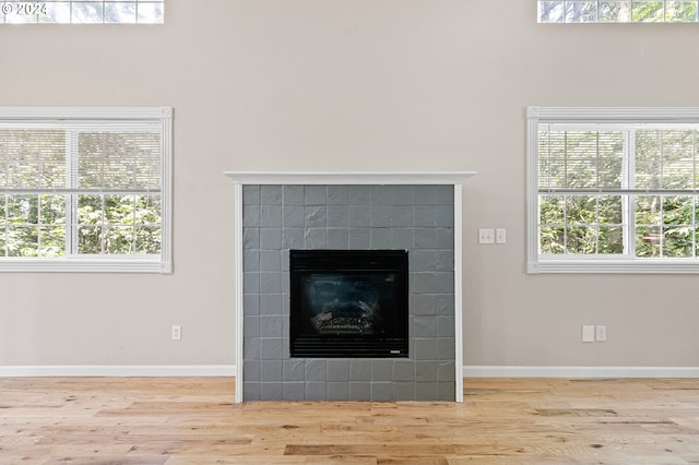 interior details with hardwood / wood-style floors and a tiled fireplace